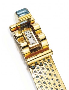 Lot 124 - Rectangular-cut  aquamarine and gold buckle clasp opening to reveal a watch dial